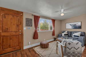 Living area featuring wood finished floors, a textured ceiling, and ceiling fan