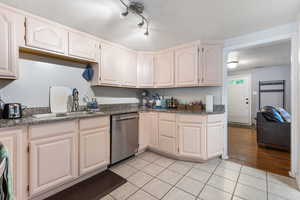 Kitchen with light tile patterned floors, a textured ceiling, dishwasher, dark stone counters, and white cabinets