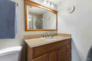Bathroom featuring a textured wall, vanity, and tiled shower