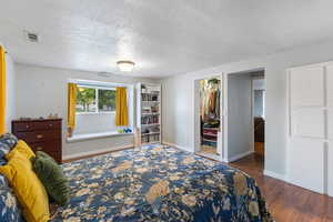 Bedroom featuring dark wood-style flooring, a textured ceiling, and a spacious closet