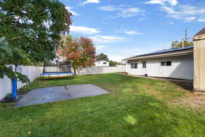 Fenced backyard with a trampoline and a patio
