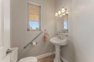 Half bath with toilet and light wood-type flooring