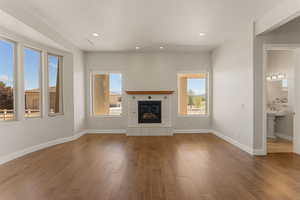 Unfurnished den featuring a fireplace, wood finished floors, and recessed lighting