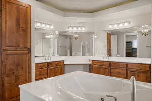 Primary bath with vanity, a garden tub, and a chandelier