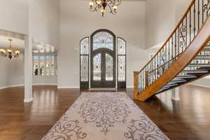 Entryway featuring a chandelier, french doors, dark wood finished floors, and a high ceiling