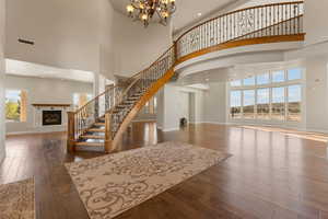 Stairs featuring a towering ceiling, a fireplace, plenty of natural light, hardwood / wood-style floors, and recessed lighting