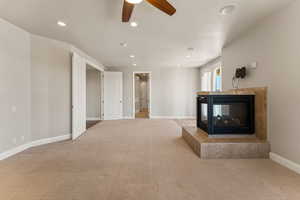 Unfurnished primary suite featuring a fireplace, carpet floors, recessed lighting, and a ceiling fan
