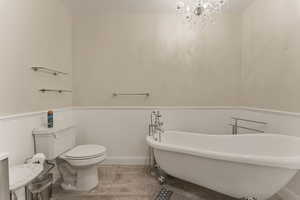 Full bathroom with a freestanding tub, wainscoting, and a chandelier