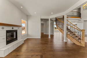 Unfurnished den with a fireplace, dark wood-type flooring, stairs, and recessed lighting