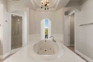 Primary bathroom featuring a whirlpool tub, a chandelier, and a shower stall