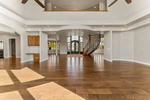 Unfurnished living room with a ceiling fan, stairs, recessed lighting, dark wood finished floors, and french doors