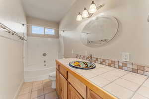 Bathroom featuring shower / tub combination, vanity, and light tile patterned flooring