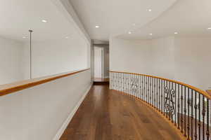 Hall featuring dark wood-style flooring, recessed lighting, and an upstairs landing