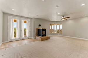 Unfurnished primary suite with a tiled fireplace, recessed lighting, a textured ceiling, light colored carpet, and a ceiling fan