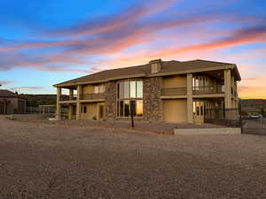 View of front of home featuring a balcony, stucco siding, a chimney, and stone siding