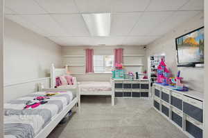 Bedroom featuring light colored carpet and a paneled ceiling