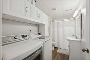 Laundry room with a paneled ceiling, dark wood-type flooring, and separate washer and dryer
