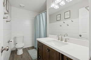 Bathroom featuring vanity, dark wood finished floors, wooden walls, and curtained shower