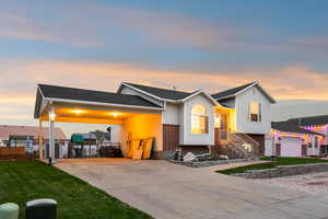 View of front of home with driveway, an attached carport, brick siding, and a front yard