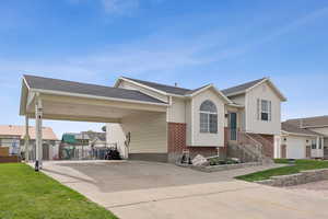 View of front of home featuring an attached carport, concrete driveway, brick siding, and a front lawn