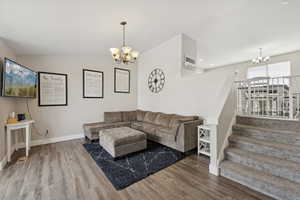 Living room with a chandelier, wood finished floors, and stairway