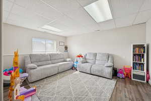 Living room with a paneled ceiling and dark wood-type flooring
