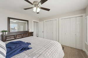Bedroom with carpet floors, multiple closets, and ceiling fan