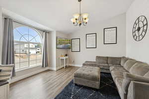 Living room featuring vaulted ceiling, wood finished floors, and a chandelier