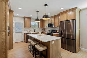 Kitchen featuring stainless steel appliances, a kitchen island, a breakfast bar area, decorative backsplash, and pendant lighting