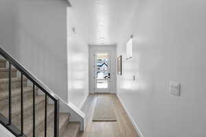 Entryway with a textured ceiling, wood finished floors, and stairway