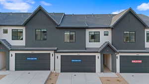 View of front of home with stucco siding, concrete driveway, a tile roof, and an attached garage