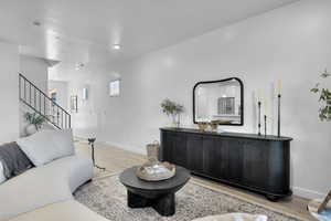 Living room featuring stairs, light wood-type flooring, and a textured ceiling