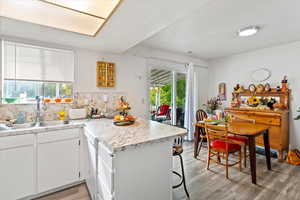 Unit 2 Kitchen featuring light countertops, a peninsula, white cabinetry, light wood-style flooring, and tasteful backsplash
