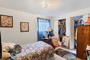 Unit 3 Carpeted bedroom featuring a textured ceiling and two closets