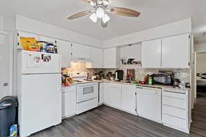 Unit 1 Kitchen featuring white appliances, white cabinetry, light countertops, dark wood finished floors, and tasteful backsplash