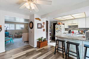 Unit 3 Kitchen featuring a breakfast bar area, white cabinets, white appliances, decorative backsplash, and light wood-style flooring