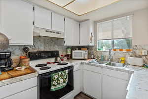 Unit 2 Kitchen with white cabinets, electric stove, light countertops, and backsplash