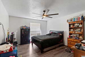 Unit 1 Bedroom featuring wood finished floors, a textured ceiling, and ceiling fan