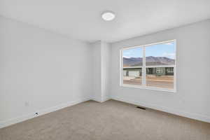 Carpeted empty room with a mountain view and baseboards