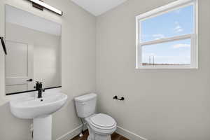 Half bathroom with baseboards and dark wood-type flooring