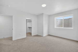 Unfurnished bedroom featuring a spacious closet and light colored carpet