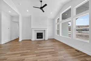 Unfurnished living room with a fireplace, a ceiling fan, light wood finished floors, recessed lighting, and high vaulted ceiling