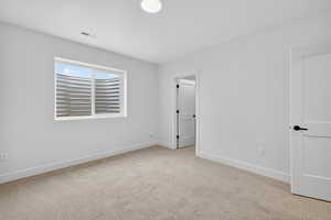 Empty room featuring light colored carpet and baseboards