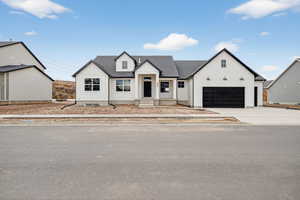 Modern farmhouse featuring board and batten siding, concrete driveway, and a shingled roof