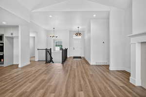 Unfurnished living room with recessed lighting, light wood-style floors, and a chandelier