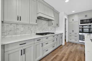 Kitchen featuring premium range hood, recessed lighting, light wood-style floors, decorative backsplash, and stainless steel appliances