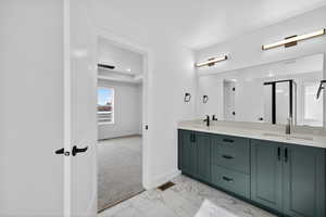 Bathroom featuring double vanity, light marble finish floors, and a shower stall
