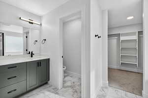 Full bathroom featuring vanity, a spacious closet, and light marble finish flooring