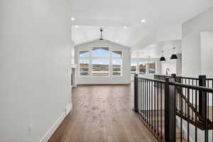 Corridor with vaulted ceiling, a chandelier, light wood-type flooring, an upstairs landing, and recessed lighting