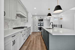 Kitchen featuring gray cabinetry, recessed lighting, decorative backsplash, hanging light fixtures, and light wood-style flooring
